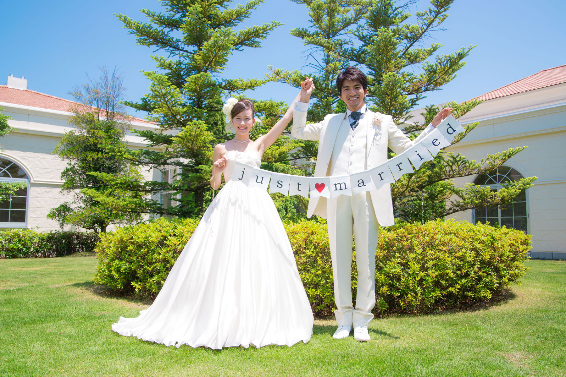 ガーデンでJust Marriedのガーランドを持つ新郎新婦